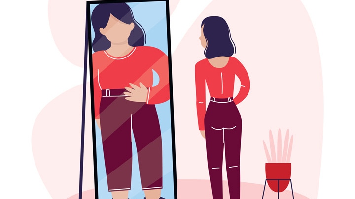 kobieta cierpiąca na anoreksję stojąca przed lustrem