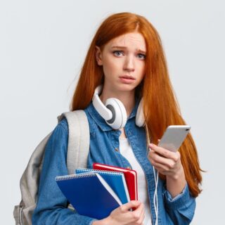 ruda dziewczyna z słuchawkami na uszach trzymająca w ręce telefon